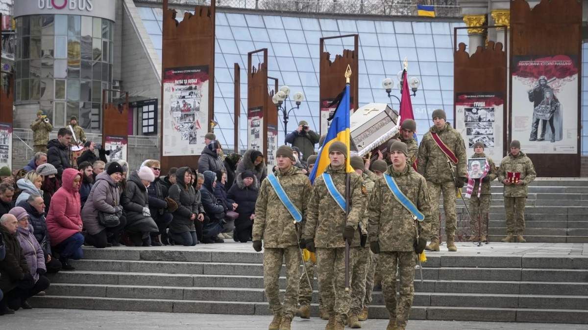 Unas personas se arrodillan mientras militares ucranianos cargan el ataúd de su compañero Oleh Yurchenko, quien murió en un enfrentamiento contra fuerzas rusas en la región de Donetsk, durante una ceremonia en Kiev
