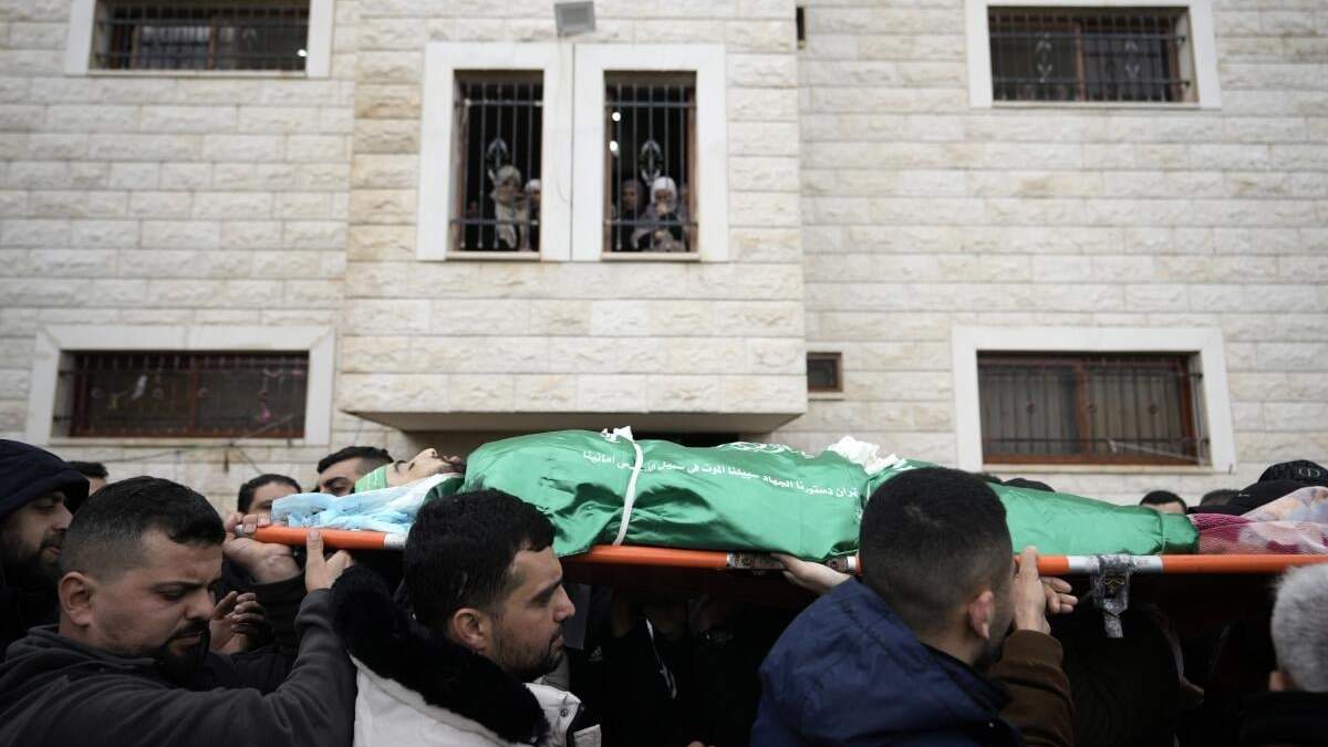 Dolientes palestinos cargan el cuerpo de Muhammad Jalamneh, envuelto en la bandera del grupo armado Hamás, durante su funeral tras ser asesinado en un asalto a hospital Ibn Sina en la localidad cisjordana de Yenín