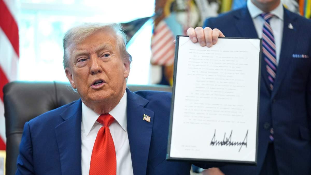 El presidente Donald Trump sostiene una orden ejecutiva firmada que requiere que el Departamento de Justicia investigue los casos de quema de banderas, en la Oficina Oval de la Casa Blanca, el lunes 25 de agosto de 2025, en Washington