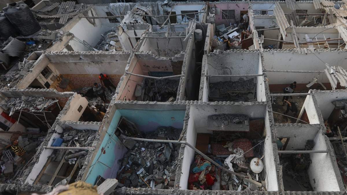 Los palestinos observan la destrucción después de un ataque israelí contra un edificio residencial en Rafah