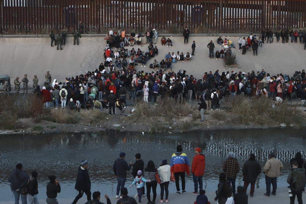 Migrantes se reúnen a orillas del río Bravo frente al muro fronterizo ente El Paso, Texas, y Ciudad Juárez, Chihuahua, el 20 de diciembre de 2022
