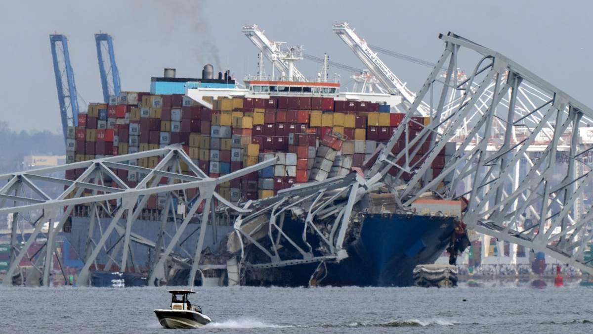 Un barco pasa frente a un buque portacontenedores que chocó contra el puente Francis Scott Key