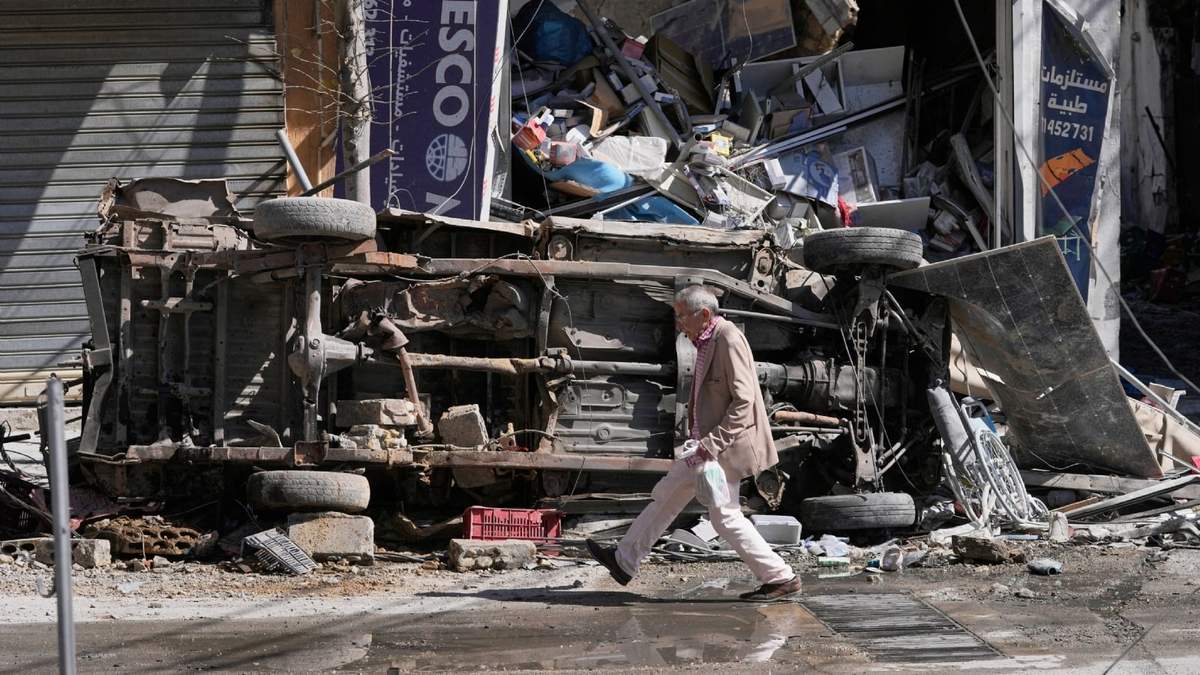 Un hombre pasa junto a un automóvil y una tienda destruidos en una calle comercial que fue alcanzada por los ataques aéreos israelíes en la ciudad de Nabatiyeh, en el sur del Líbano, el jueves 5 de marzo de 2026