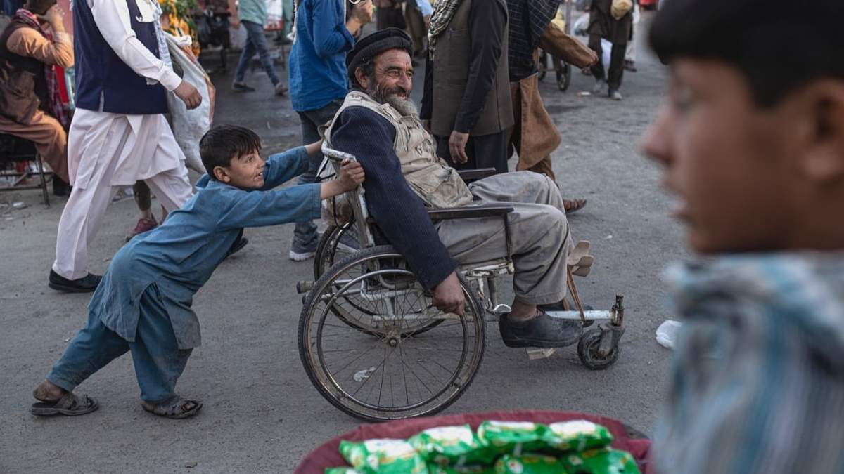 Un niño empuja la silla de ruedas de un adulto en Kabul