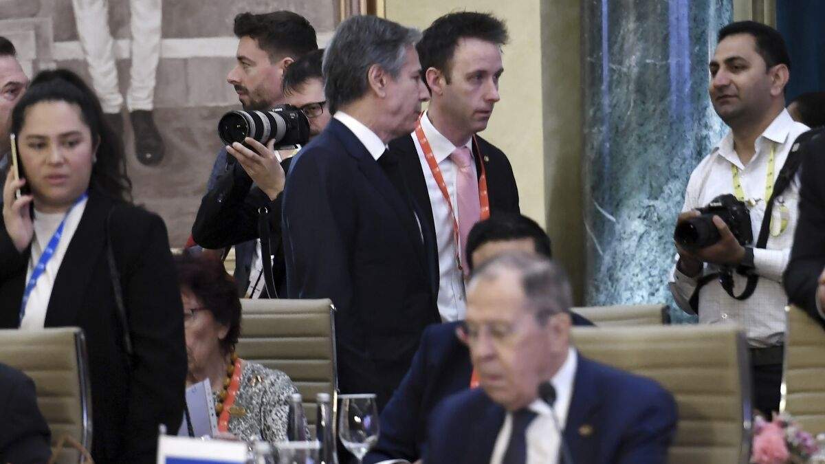 El secretario de Estado de Estados Unidos, Antony Blinken (centro, arriba), pasa junto al ministro de Exteriores de Rusia, Sergéi Lavrov, durante una reunión de cancilleres del Grupo de los 20 en Nueva Delhi, en India