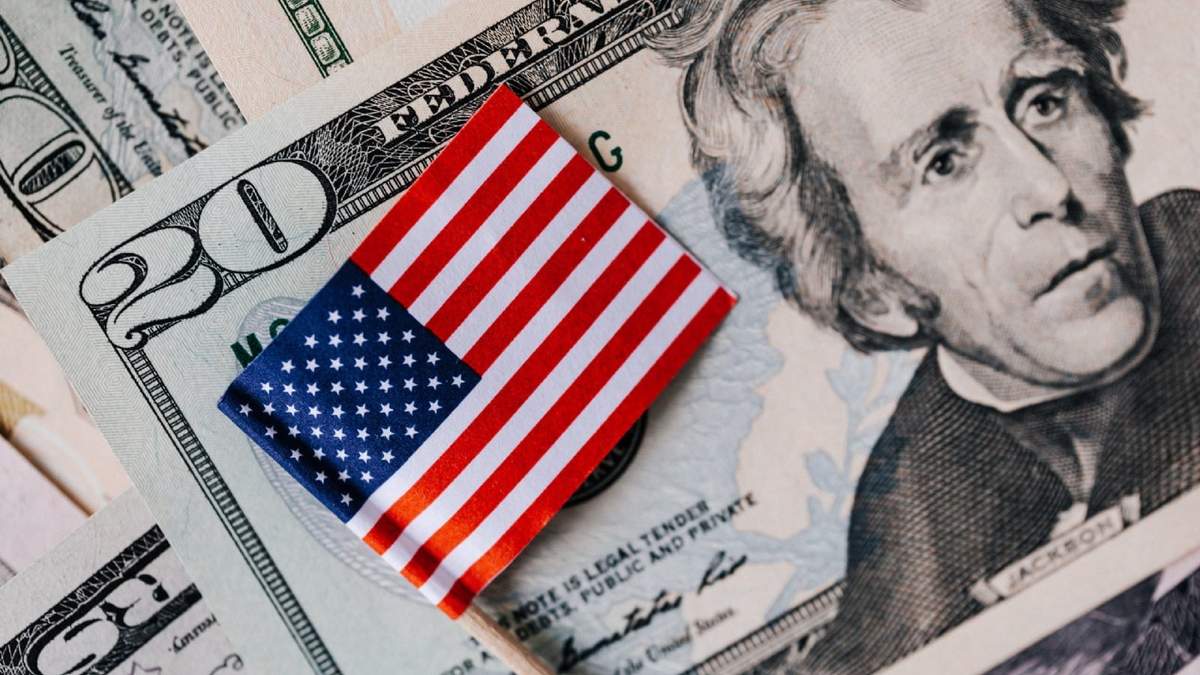 Un billete de 20 dólares junto a una bandera de Estados Unidos. Fuente: (Twitter)