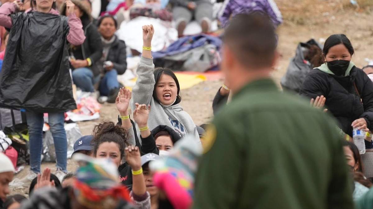 Mujeres muestran sus pulseras con la esperanza de ser elegidas para que su solicitud de asilo sea atendida
