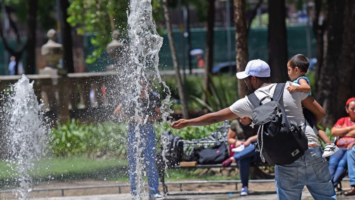 Un hombre se refresca en una fuente de la CDMX