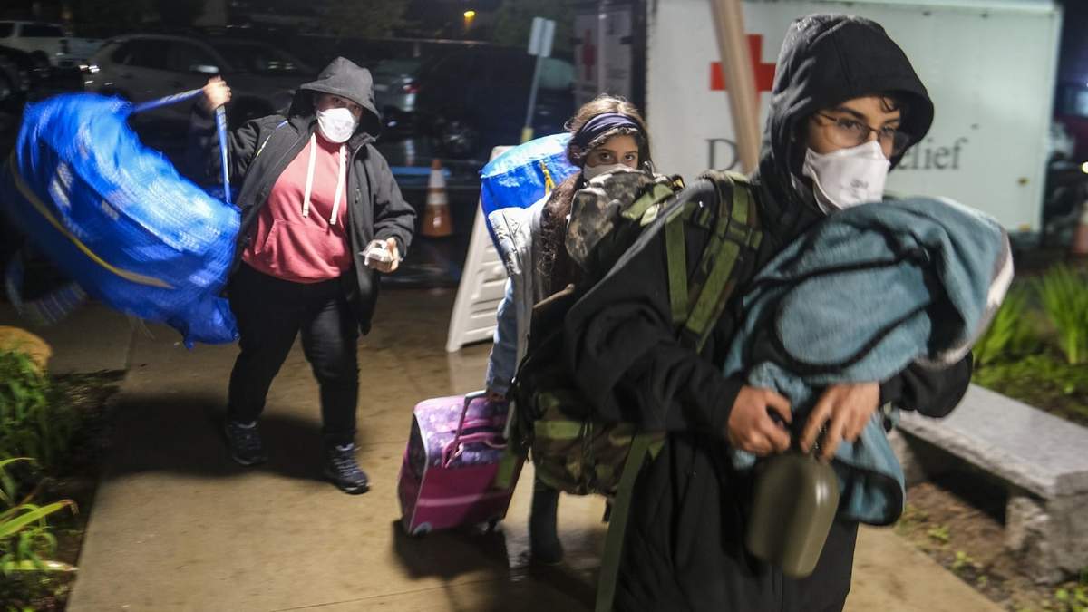 Gente carga sus pertenencias a su llegada a un centro de evacuación en Santa Bárbara, California