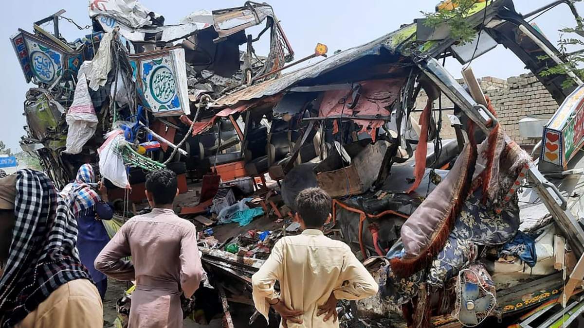 Residentes locales miran a los restos de un autobús en el lugar de un accidente cerca de Dera Ghazi Khan, Pakistán el lunes 19 de julio de 2021. Decenas de personas murieron y resultaron heridas en el siniestro en el centro de Pakistán