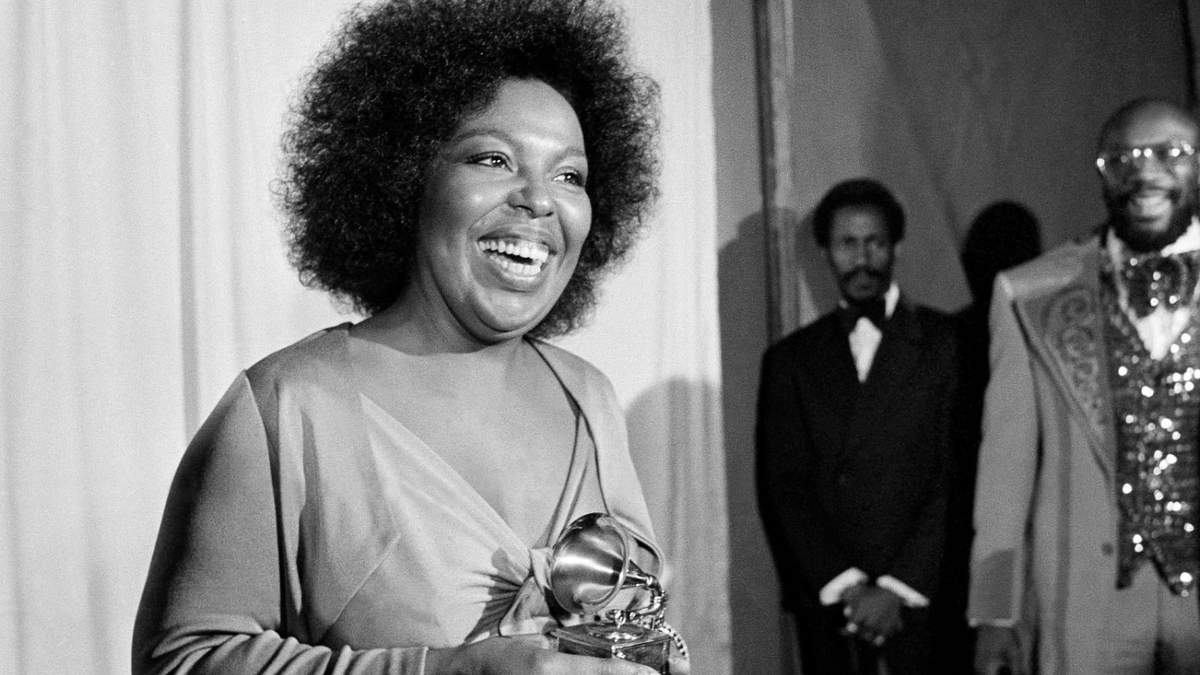 Roberta Flack sonríe mientras sostiene el premio Grammy que recibió por su álbum "Killing Me Softly With His Song" ante la mirada del cantante Isaac Hayes, derecha, en la entrega de los premios Grammy en Los Ángeles, el 4 de marzo de 1974