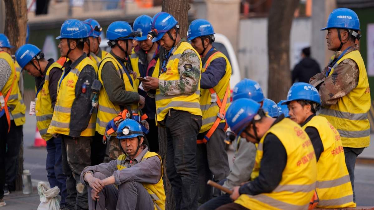 Trabajadores esperan transporte afuera de una obra en Pekín