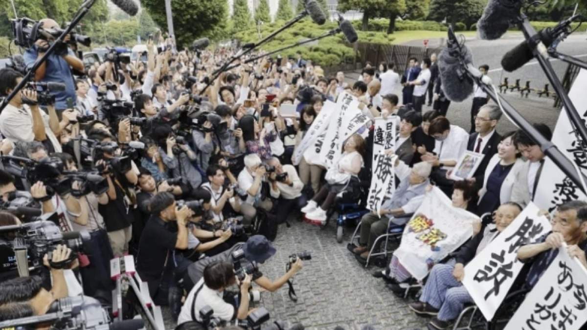 Demandantes, sus abogados y simpatizantes sostienen letreros que dicen “Ganamos la demanda” afuera de la Corte Suprema en Tokio, Japón