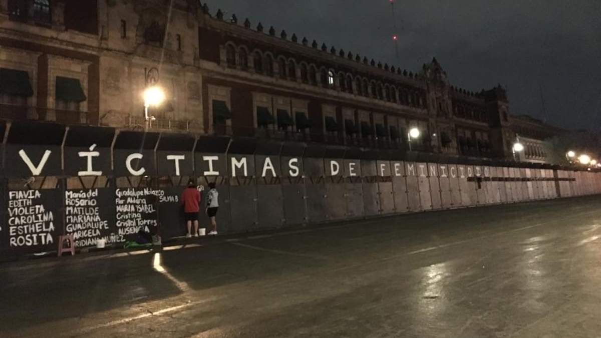 Activistas pintan los nombres de mujeres asesinadas en las vallas colocadas en Palacio Nacional