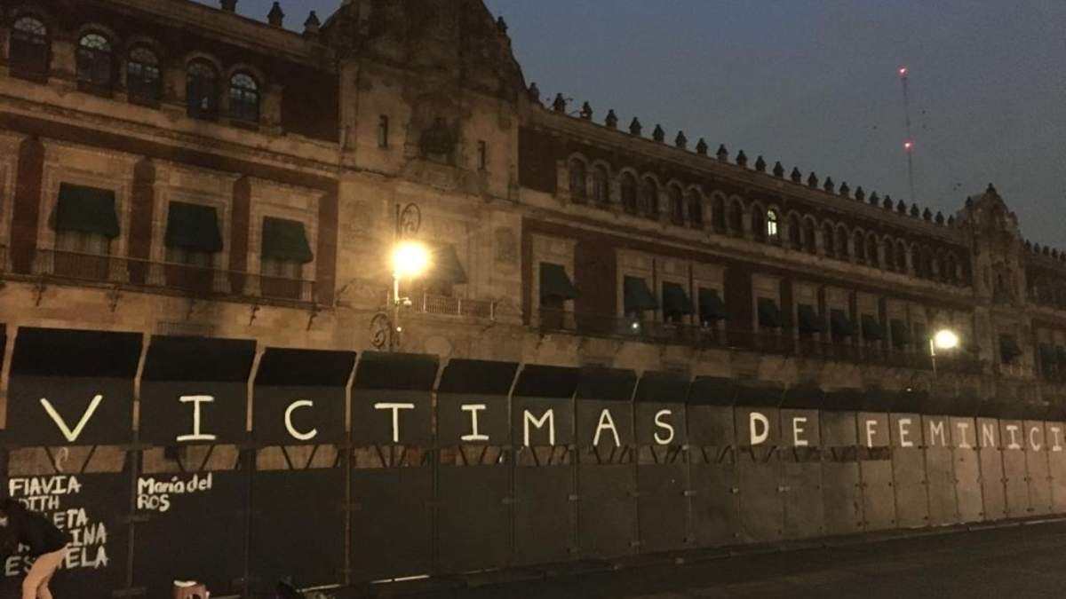 Activistas pintan los nombres de mujeres asesinadas en las vallas colocadas en Palacio Nacional