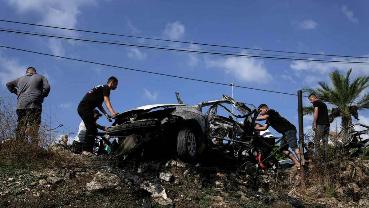 Palestinos se acercan a un auto destruido por el ataque de un dron en la localidad de Zeita, al norte de la ciudad cisjordana de Tulkarem, el 3 de agosto de 2024. (AP Foto/Majdi Mohammed)