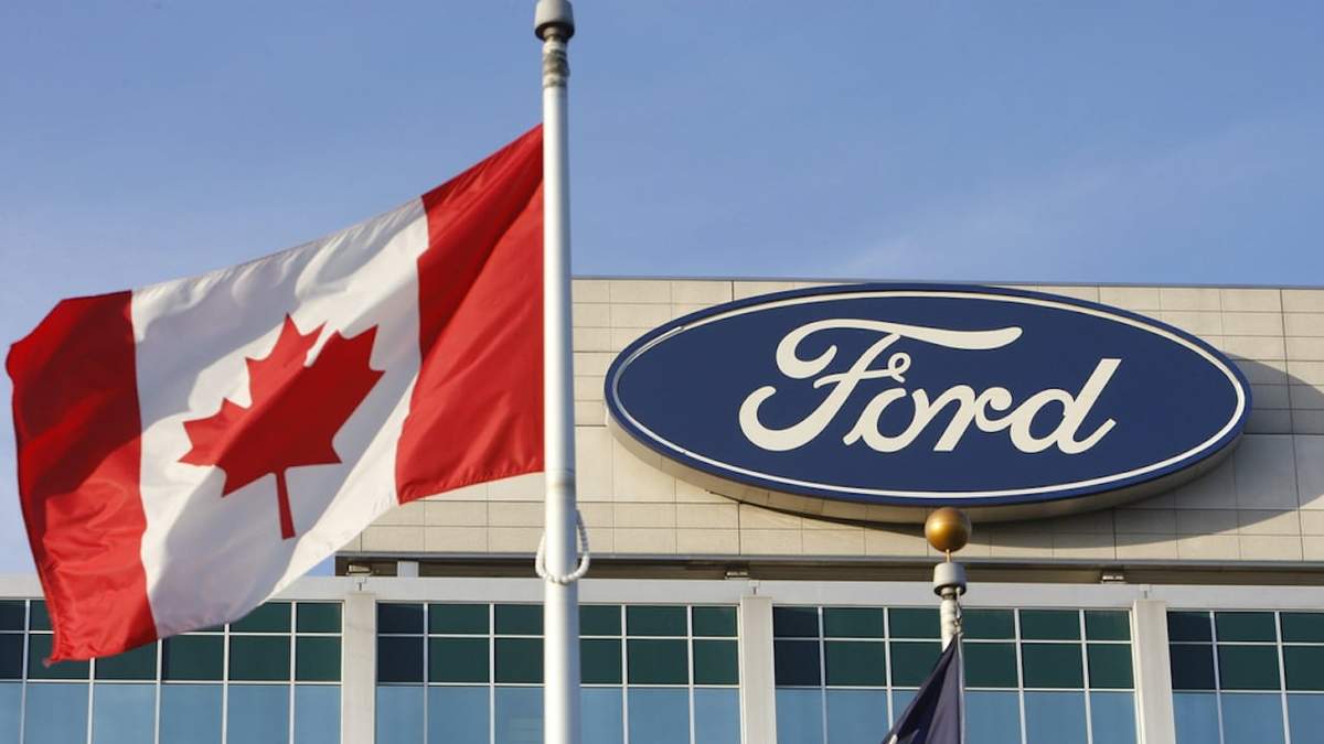Una bandera canadiense ondea frente al logotipo de Ford en la sede de la compañía en Dearborn, Michigan