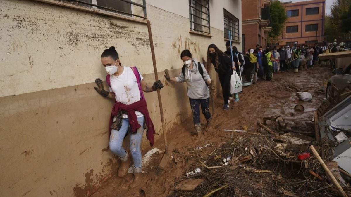 Voluntarios caminan entre el lodo para colaborar en las tareas de limpieza tras las inundaciones que arrasaron Massanassa, a las afueras de Valencia, el 2 de noviembre de 2024