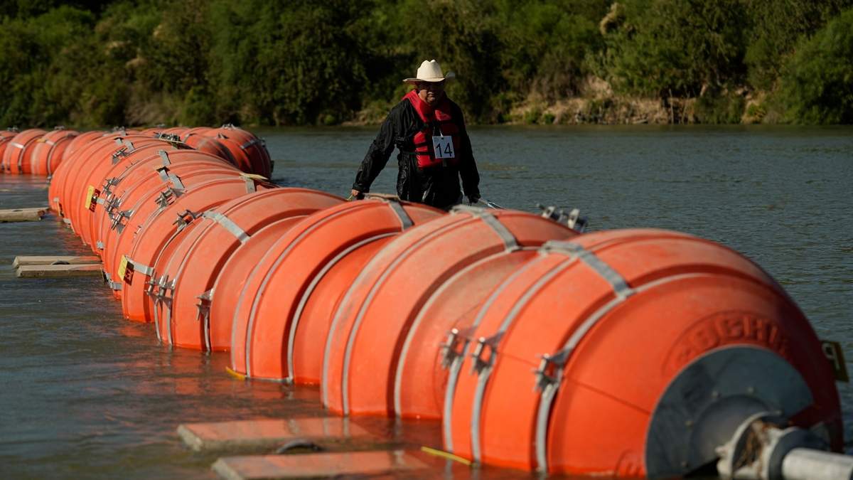Una persona en kayak pasa al lado de boyas instaladas como barrera en el Río Grande (o Bravo), el 1 de agosto de 2023, en Eagle Pass, Texas