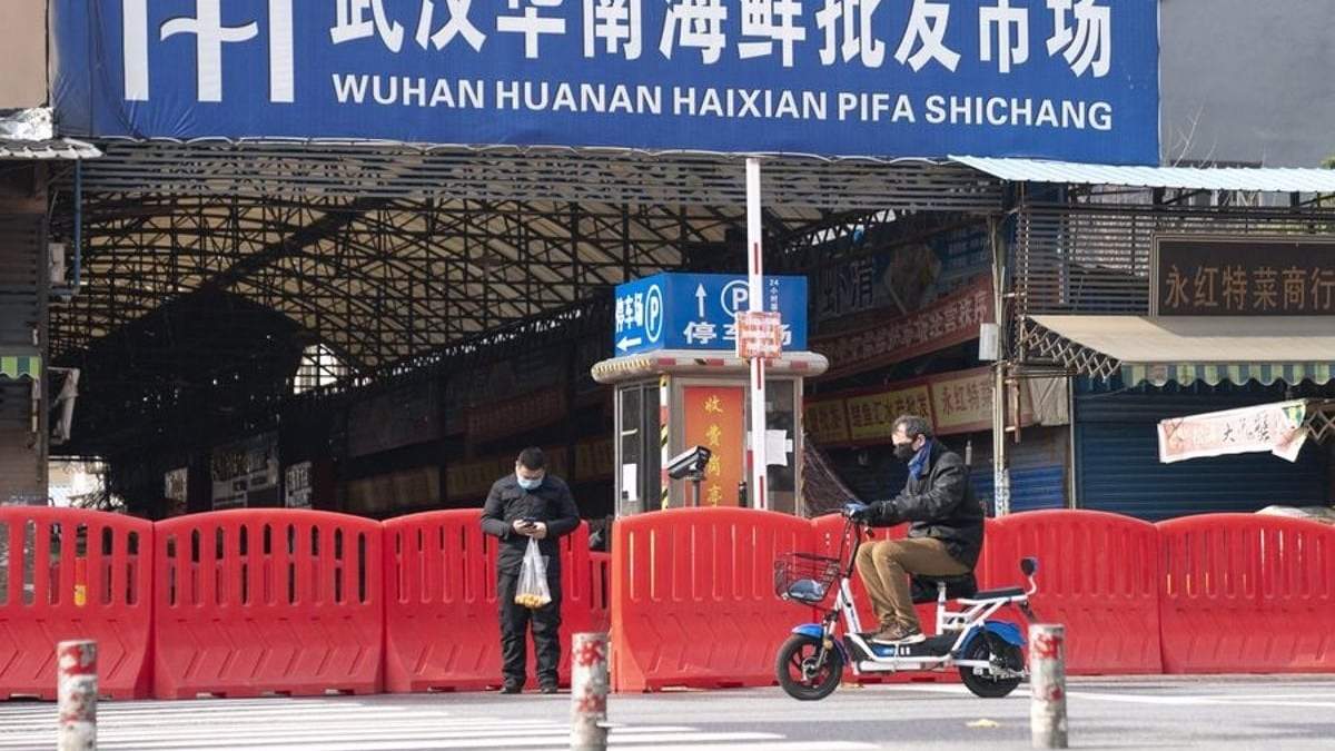 Dos ciudadanos pasan por la entrada del mercado de mariscos Huanan en Wuhan