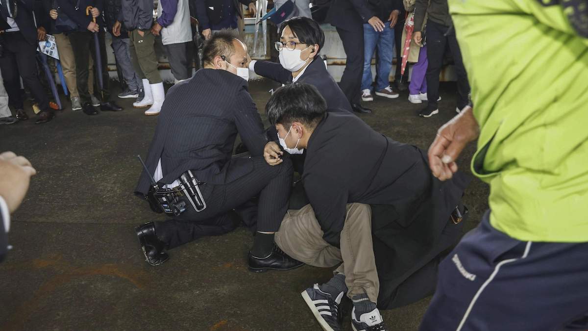 Policías someten contra el piso a un hombre que al parecer lanzó una bomba de humo durante la visita del primer ministro Fumio Kishida a un puerto en la prefectura de Wakayama