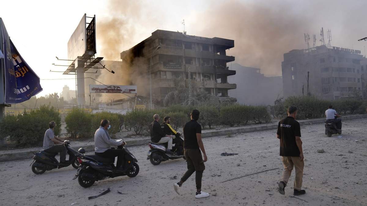 Gente pasa ante edificios destruidos que fueron alcanzados por bombardeos israelíes en Dahiyeh, Beirut, Líbano