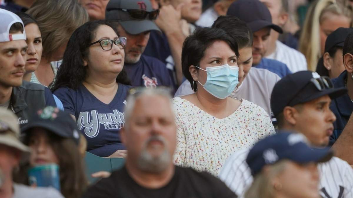 Una persona en las gradas usa un cubrebocas durante el juego de béisbol entre los Marineros de Seattle y los Yankees de Nueva York