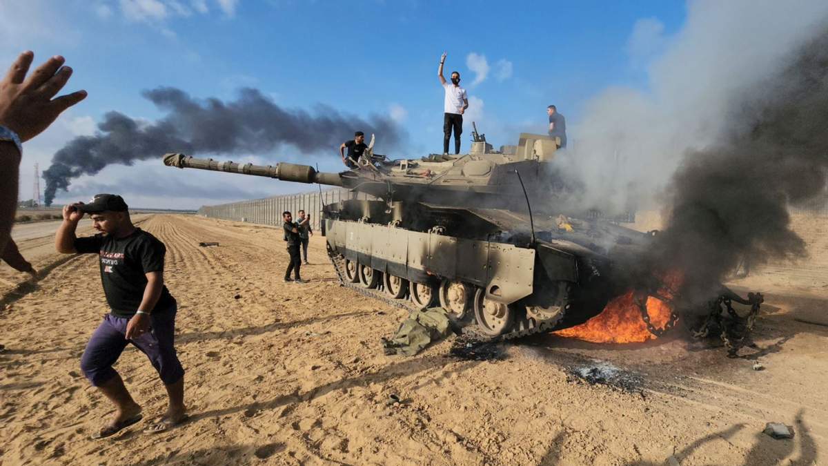 Los palestinos celebran junto a un tanque israelí destruido en la valla de la Franja de Gaza al este de Khan Youni