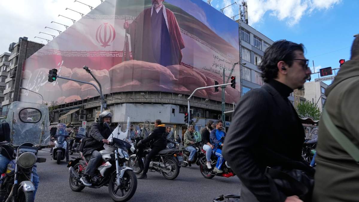 Varias personas pasan en sus motocicletas frente a una valla publicitaria que muestra una imagen del líder supremo de Irán, el ayatolá Mojtaba Khamenei, en el centro de Teherán, Irán, el lunes 6 de abril de 2026