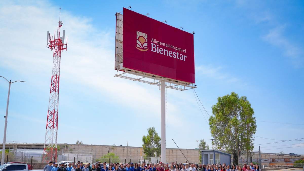Personal de la Unidad Operativa de Alimentación Para el Bienestar de Zacatecas frente a un espectacular de la dependencia