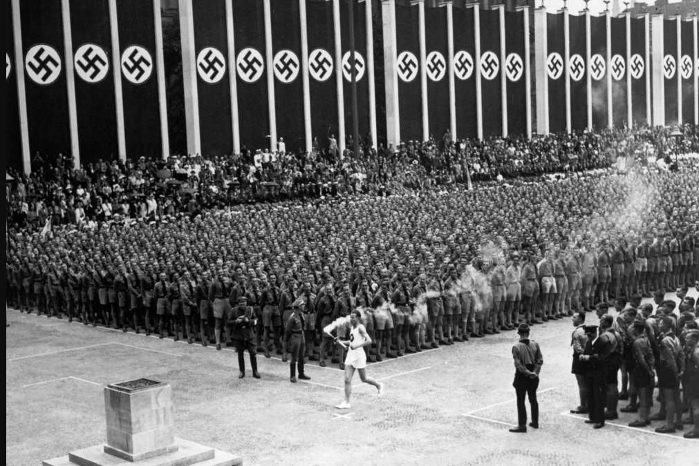 Un corredor lleva la antorcha olímpica al Estadio Olímpico para encender el pebetero en la Olimpiada de 1936