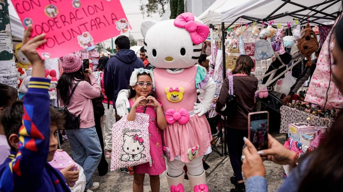 Una fan del personaje japonés Hello Kitty posa para una foto con una persona disfrazada de Hello Kitty en un mercado callejero en la Ciudad de México