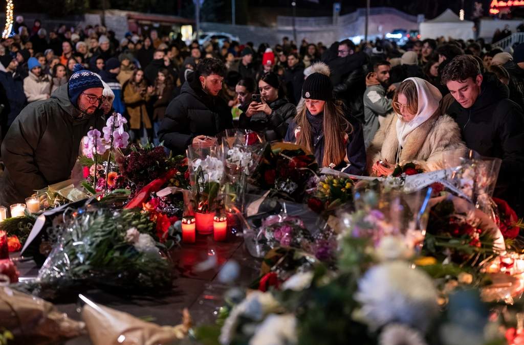 Varias personas encienden velas y dejan flores cerca del bar Le Constellation, donde un devastador incendio dejó decenas de muertos y heridos durante una fiesta de Año Nuevo, en Crans-Montana, Suiza, el 1 de enero de 2026