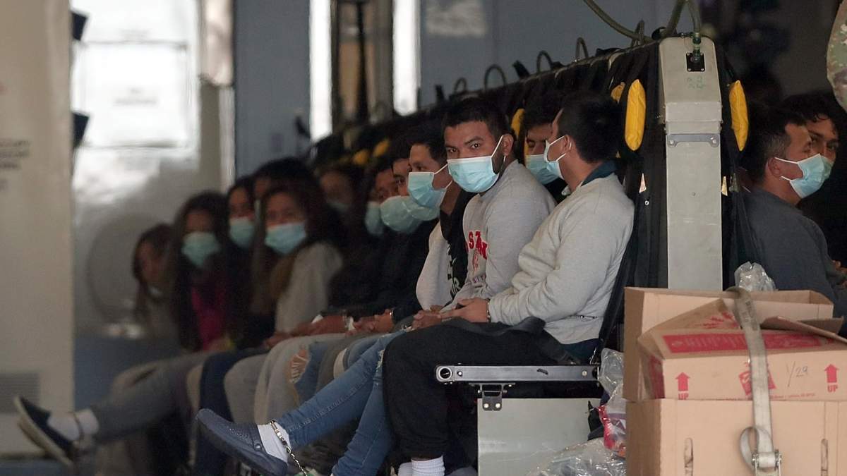 Migrantes con cubrebocas y esposados de manos y pies a bordo de una aeronave militar en Fort Bliss, en El Paso, Texas, mientras esperan a ser deportados a Guatemala