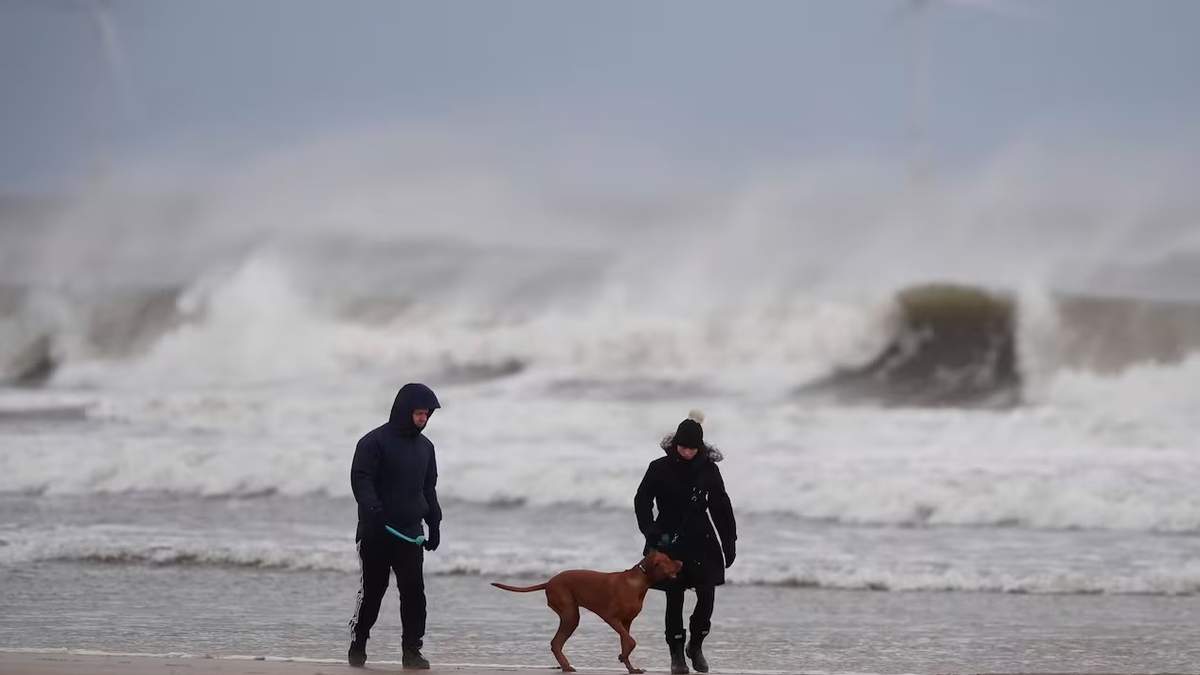 Una pareja pasea a sus perros en Tynemouth Longsandsm en la costa noreste de Newcastle, Inglaterra