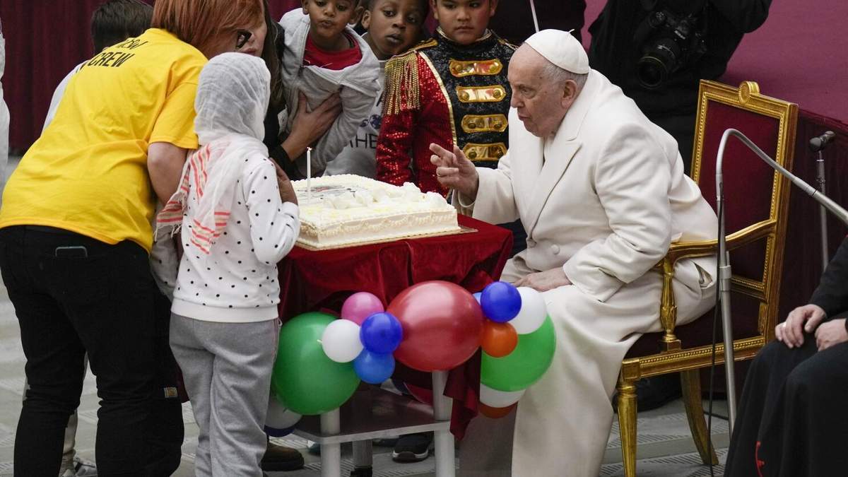 Francisco sopla una vela sobre un pastel mientras celebra su cumpleaños con niños en el Aula Pablo VI del Vaticano