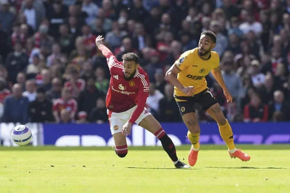 Noussair Mazraoui, del Manchester United (izquierda), y Matheus Cunha, del Wolverhampton Wanderers, disputan el balón durante el partido de la Premier League inglesa entre el Manchester United y el Wolverhampton Wanderers, en Old Trafford, Manchester, Inglaterra, el domingo 20 de abril de 2025.