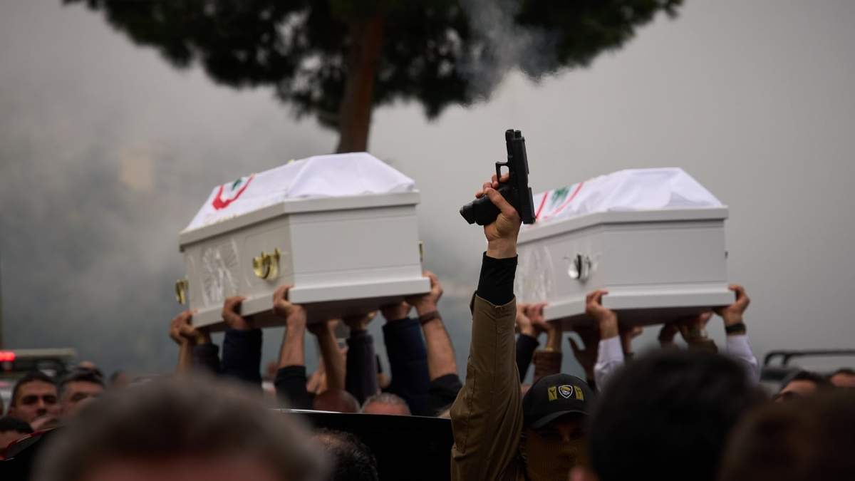 Una persona dispara una pistola mientras otros llevan los féretros de Pierre Mouawad, del partido Fuerzas Libanesas, y su esposa, en el funeral en Yahshush, Líbano, el 7 de abril del 2026