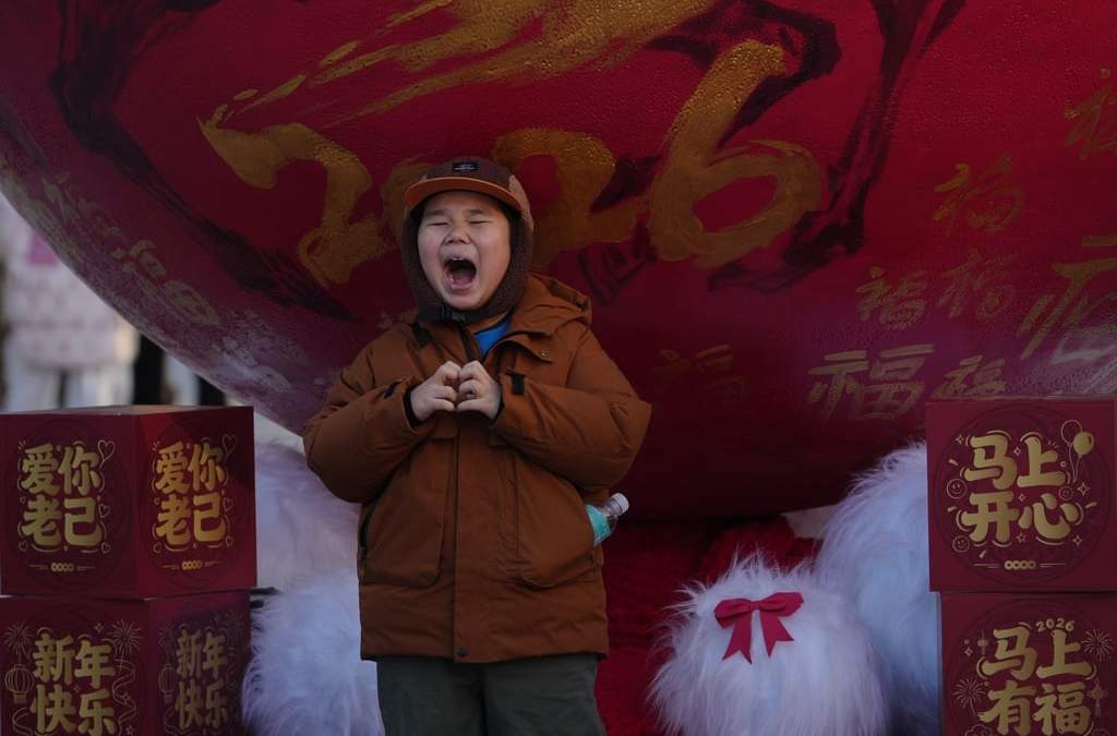 Un niño posa para una foto con decoraciones para llamar a la prosperidad antes del inicio de 2026, el Año del Caballo según el horóscopo chino, en un distrito comercial en Beijing, el 31 de diciembre de 2025