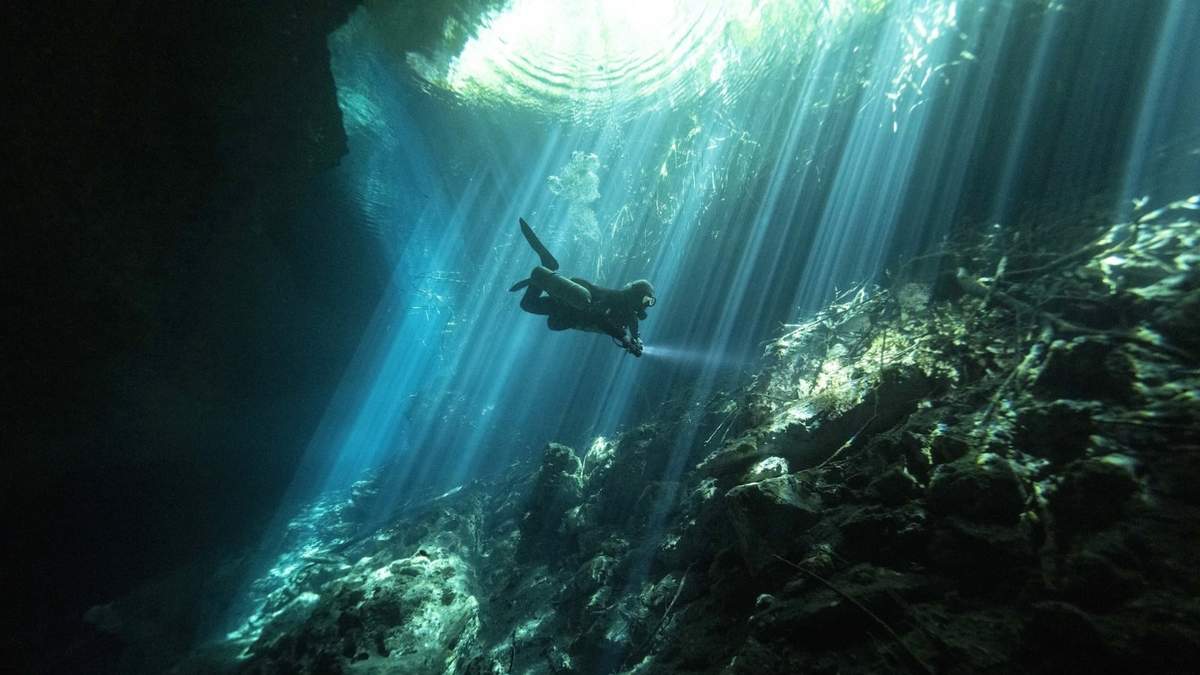 Peter Broger, instructor de buceo en cuevas, explora el cenote "Jardín del Edén", mientras los rayos de sol se filtran entre el agua, cerca de Tulum