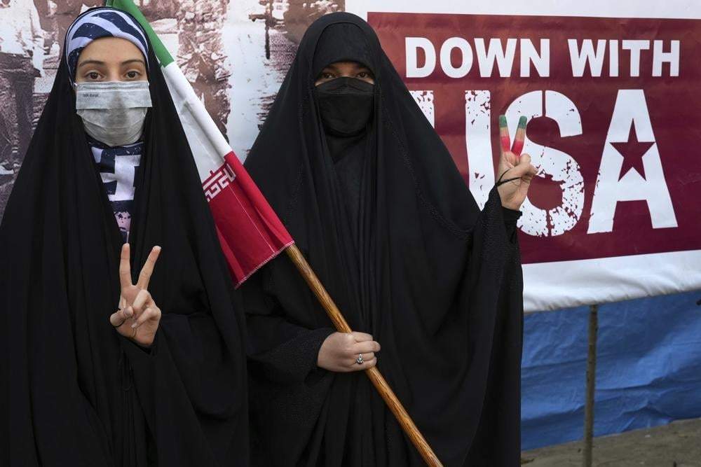 Manifestantes iraníes hacen el gesto de la victoria delante de una pancarta contra Estados Unidos durante una manifestación anual frente a la antigua embajada estadunidense en Teherán, Irán