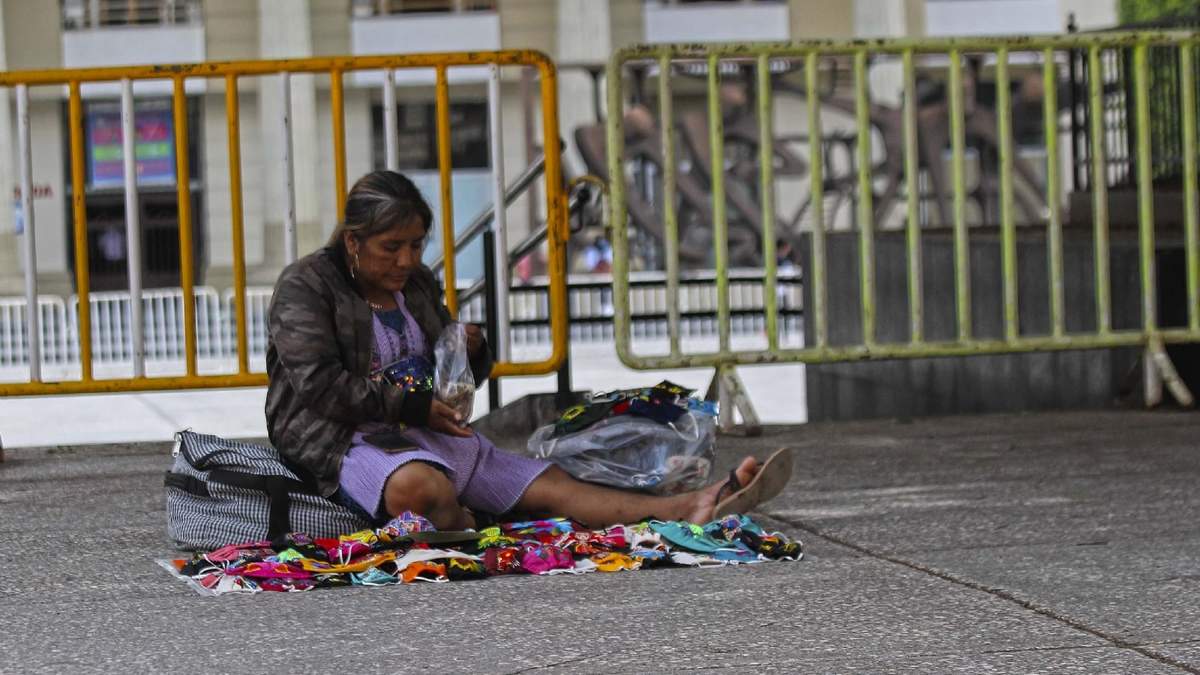 Una mujer ofreces sus cubre-bocas artesanales en la plaza