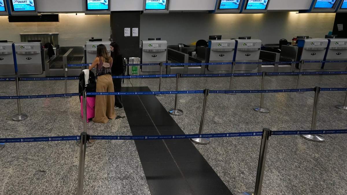 Los viajeros permanecen frente a un área de facturación desatendida durante una huelga sindical contra un proyecto de ley de reforma laboral en un aeropuerto de Buenos Aires, Argentina