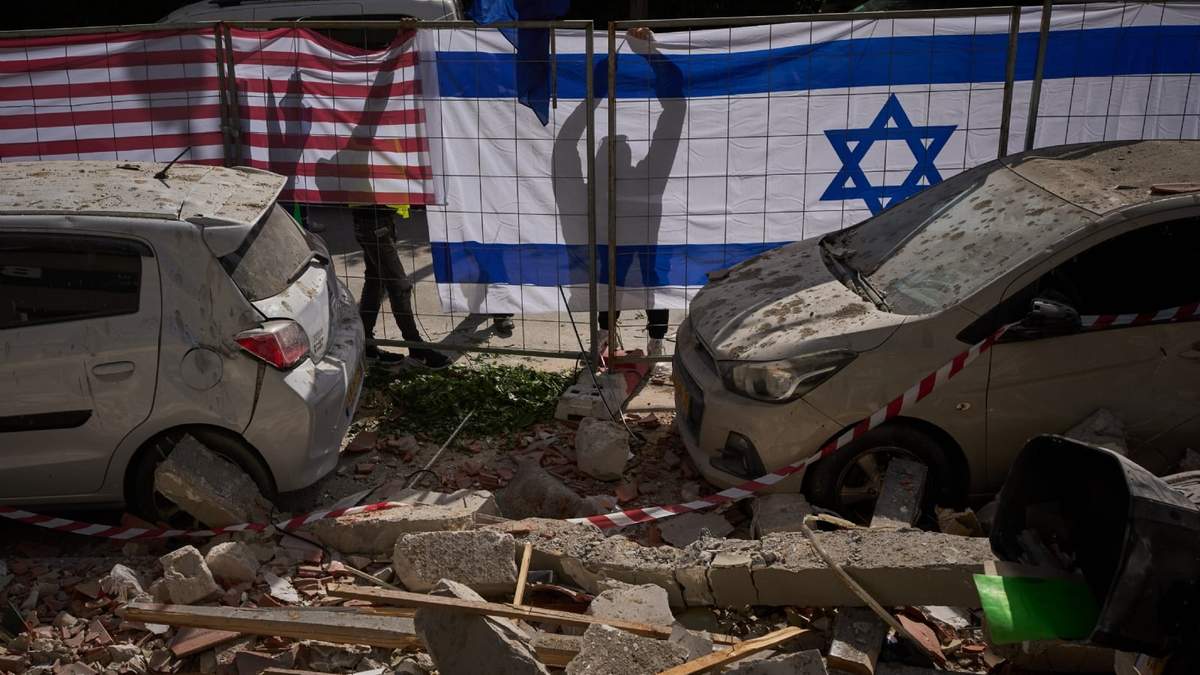 Autoridades israelíes colocando banderas israelíes y estadounidenses en un lugar alcanzado por un misil iraní que mató a dos personas en Ramat Gan, Israel, el miércoles 18 de marzo de 2026