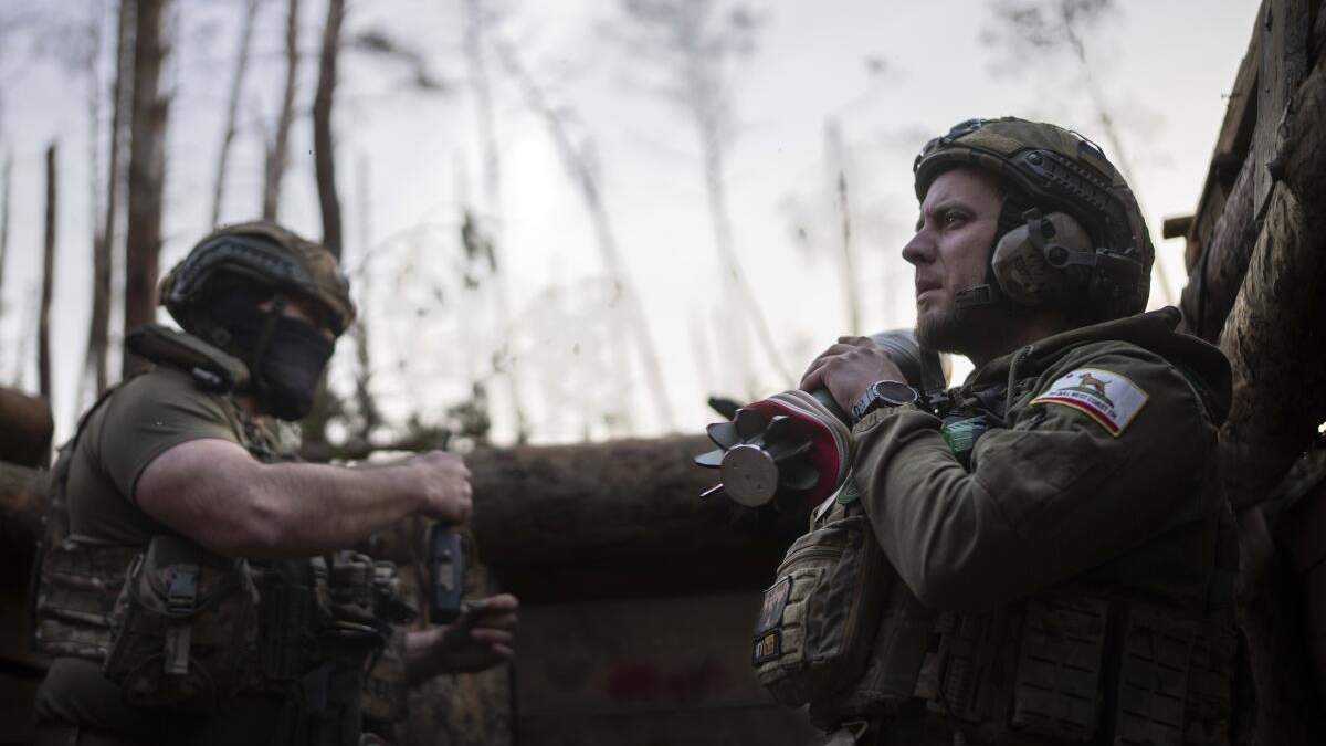 Un soldado ucraniano de la brigada Azov, conocido por su apodo Chaos, a la derecha, lleva un mortero mientras espera una orden de disparar en posiciones en torno a un kilómetro de distancia de las fuerzas rusas en el frente en dirección a Kreminna, en la región de Donetsk, Ucrania