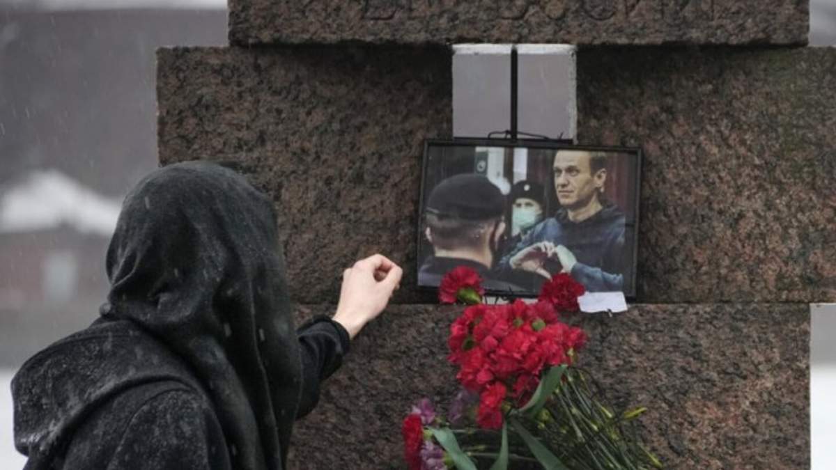 Una mujer toca la fotografía de Alexei Navalny tras dejar flores en homenaje al fallecido líder opositor ruso, en San Petersburgo, Rusia, el sábado 17 de febrero de 2024