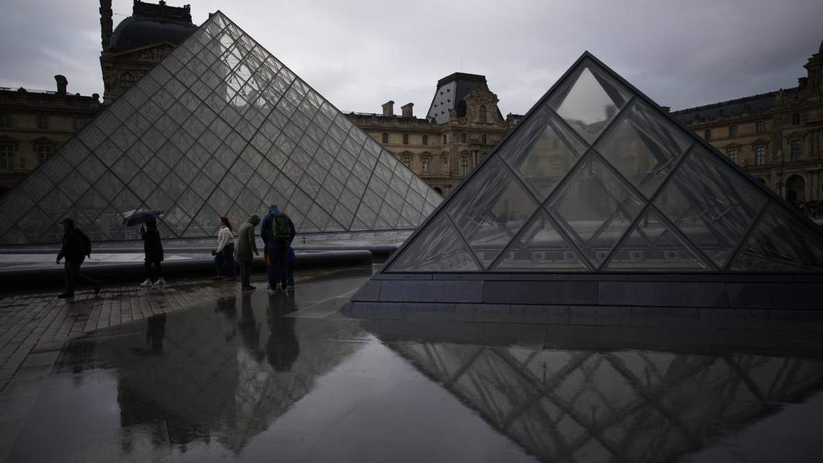 Varias personas pasean por el patio del museo del Louvre bajo la lluvia, en París, el 27 de octubre de 2025