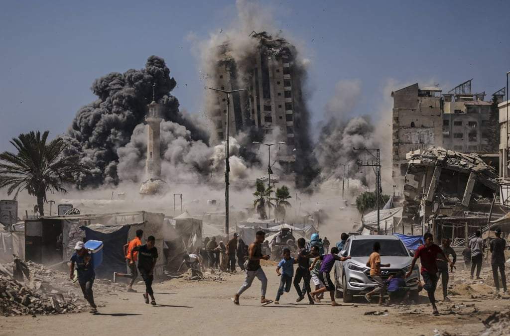 Palestinos corren para ponerse a cubierto mientras Israel ataca un rascacielos en la Ciudad de Gaza, el 5 de septiembre de 2025, tras una advertencia previa del ejército israelí