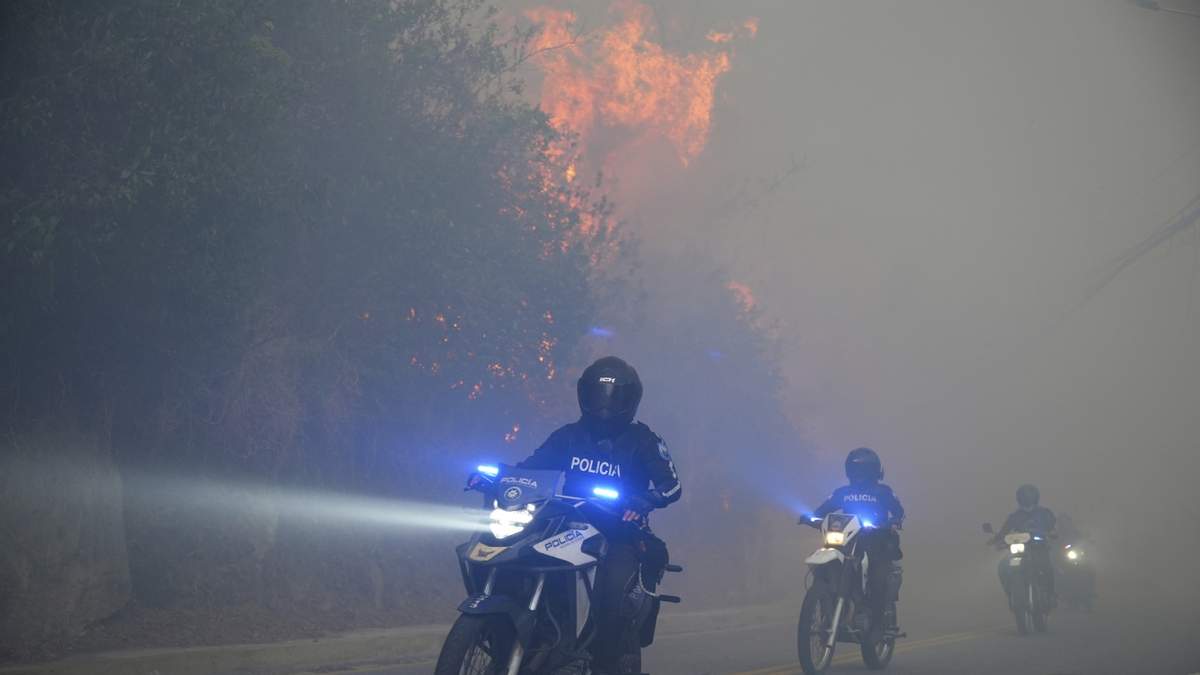 Policías pasan junto a los incendios desatados en una zona boscosa en el barrio de Guápulo en Quito