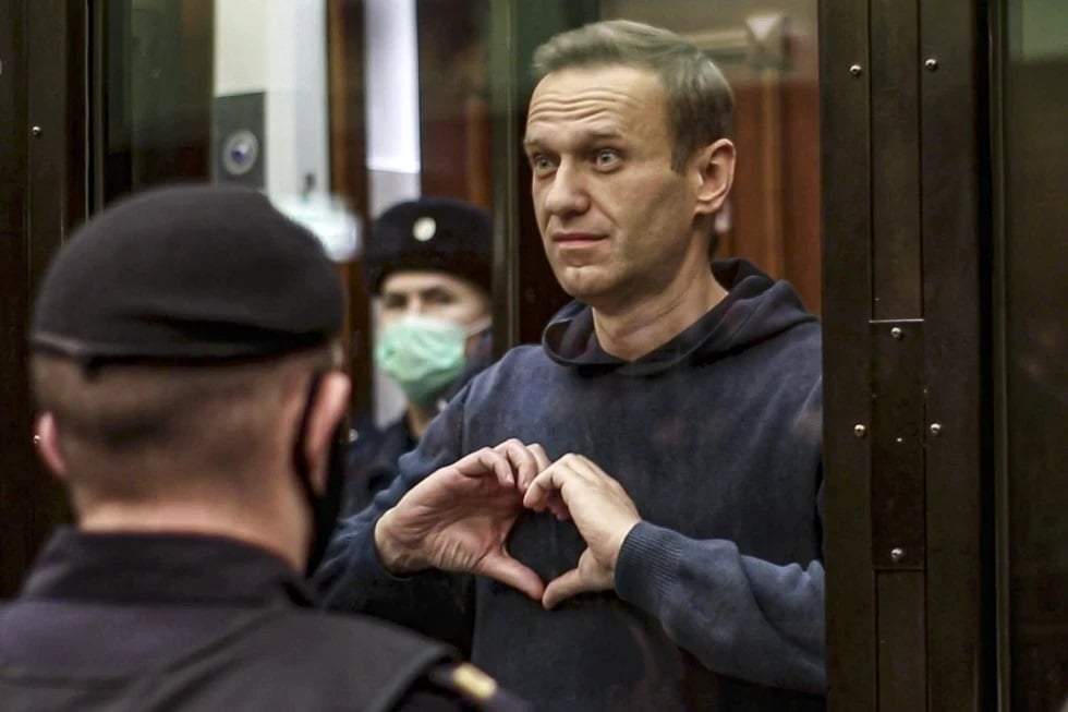 El líder opositor ruso Alexei Navalny hace un corazón con sus manos desde el espacio reservado para los acusados durante una vista en el tribunal en Moscú, en 2021